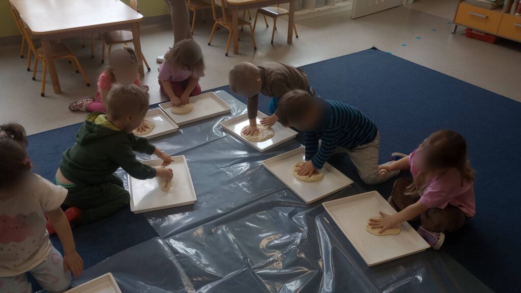 Dzieci z grupy Bociany odciskają ślady dinozaurów w masie solnej.