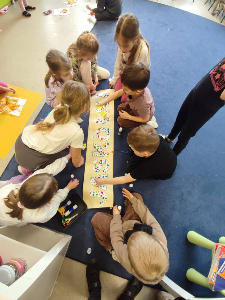 Dzieci z grupy Jaskółek w trakcie przygotowywania napisu z nazwą swojej grupy.