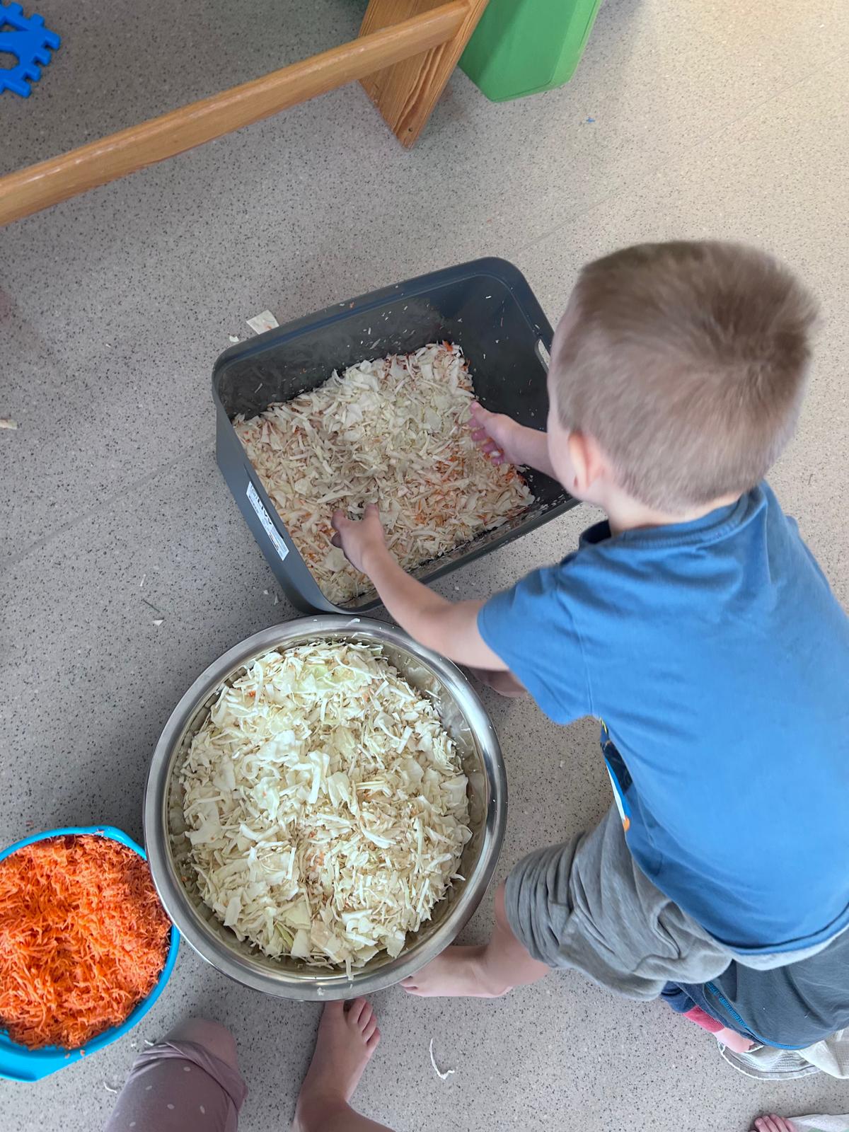 Chłopiec miesza poszatkowaną kapustę